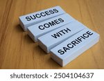 Angel view of Success Comes With Sacrifice text on white wooden blocks. Motivational and inspiration concept.