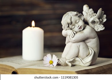 Angel, White Candle And Flower On The Book    