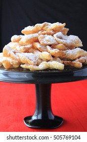 Angel Wings Cakes, Funnel Cakes On A Black Cake Stand On A Black And Red Background - Cakes Eaten Traditionally In Poland On Fat Thursday