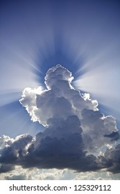 Angelic / Antrophomorphic Cloud In The Sky With Sun-rays Casting A Shadow In The Water Vapor