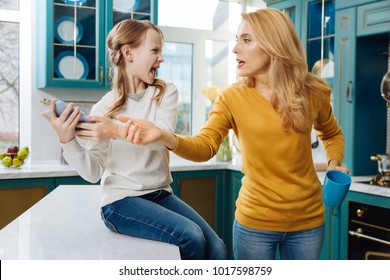 Anger. Angry Fair-haired Slim Girl Holding A Phone And Crying While Her Mom Taking It Away