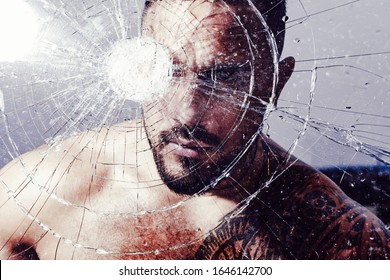 anger. destruction. bullet hole in glass. broken glass because of hit. crush test. theft. emotional discharge. hispanic man broken mirror. macho man behind crushed glass. windscreen. windscreen crack.
