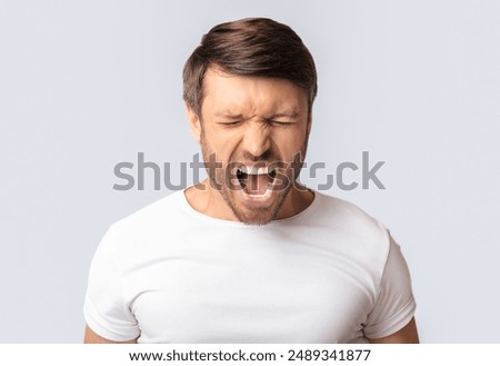 Anger Expression. Portrait Of Crazy Man Shouting Furiously Over White Studio Background. Copy Space