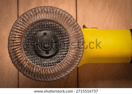 Angle grinder with abrasive flap disc on wooden flat lay background.