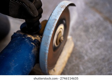 Angle grinder cutting a concrete block outdoors, rotating abrasive disc in motion, close up view of power tool used for masonry and construction work.