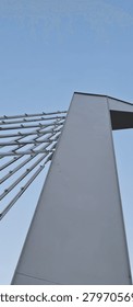 ​Low angle oblique view of a modern cable-stayed bridge pylon against a clear blue sky, abstract architectural geometry with steel cables, infrastructure and copy space background