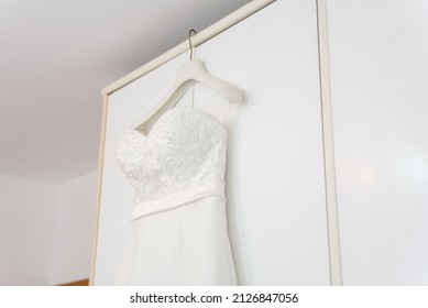 An angle shot of a wedding dress hand on a wardrobe 
