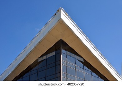 The angle of the top of the building with large cornice and dark glass wall against the blue sky. Look up.