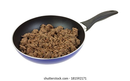 An angle view of chopped 90% lean ground beef cooking in a frying pan on white. 