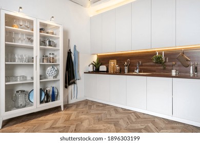 Angle view of modern interior with white kitchen cupboards, kitchenware cabinet, apron on hook and wood countertop. Copy space on wooden floor - Powered by Shutterstock