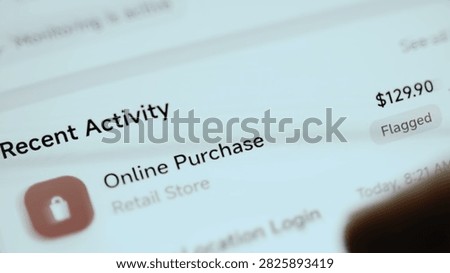 Angled close-up of a mobile banking security screen where flagged $129.90 online purchase appears in recent activity.