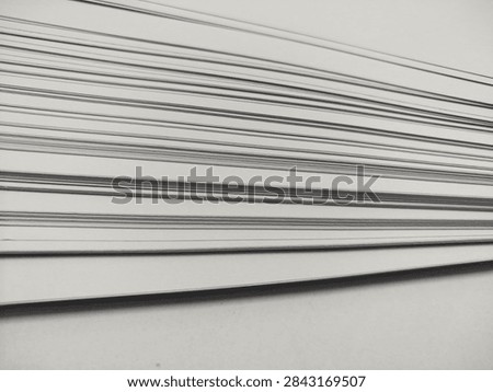An angled close-up view of multiple clean white sheets of paper stacked on top of each other, creating subtle horizontal lines and soft shadows.