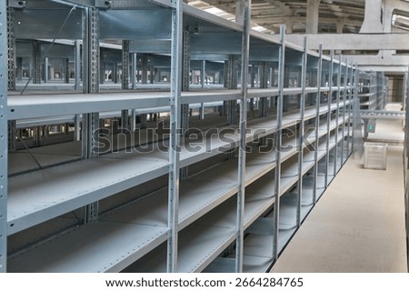 Angled close-up view of multiple rows of tall, empty metal shelving units in a warehouse or storage facility, ready for inventory. Clean and organized industrial space.