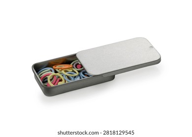 An angled studio product photograph of a rectangular metal tin box with a sliding lid partially closed, filled with an assortment of colorful spiral plastic stitch markers, isolated against a pure white background.
