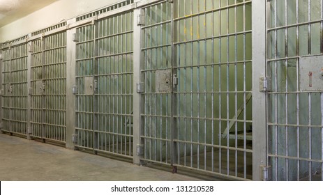 Angled view of bars in a old prison. Iron bars are showing wear, rust, and decay from being so old