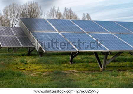 Angled view of midsized solar array on maintained grass, clear module alignment and support legs visible, crisp daylight emphasizes
