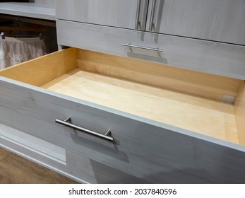 Angled view of an open, empty dresser drawer inside a large, spacious walk in closet