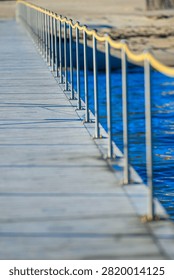Angled view of pier railing with repeating posts and soft ocean background creating abstract perspective
