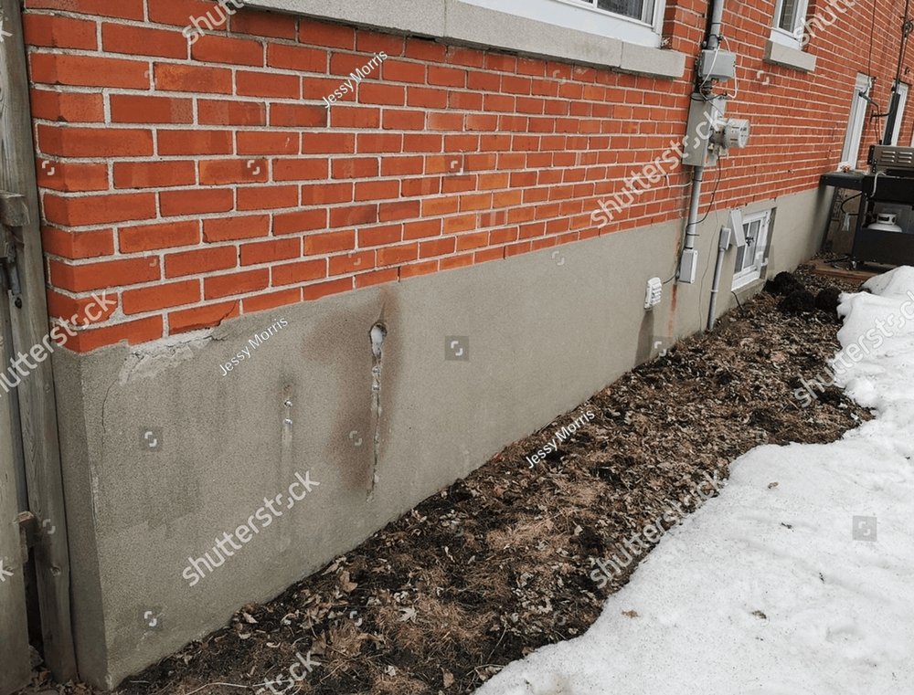 An angled view of red brick house showing a concrete foundation with an ...