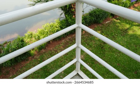 Angled view of white railing corner with grass and water in background.