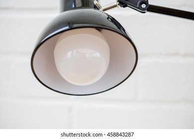 Anglepoise Lamp. Bulb And Light Close Up With White Brick Background.