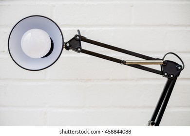 Anglepoise Lamp. Retro Black Metal Light Looking At Viewer With White Brick Background. Design Concept.