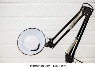 Anglepoise Lamp. Retro Metal Light Bent In Low Angle With White Brick Background