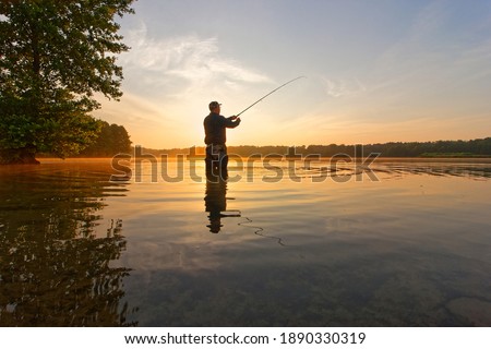 angler catching the fish during summer sunrise

