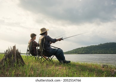 Angler friendship sitting a chair and fishing together at the lake. Camping fire on the shore of the lake. Fisherman with bonfire. Survival concept. - Powered by Shutterstock