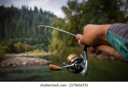 The Angler Holds A Rod With A Reel In His Hand. Close Up Fishing Objekt Background.	