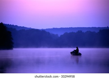 An Angler Spends A Quiet Morning On The Lake Fishing For Bass.