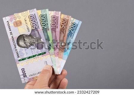 Angolan money - kwanza in the hand on a gray background