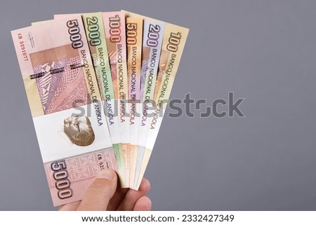 Angolan money - kwanza in the hand on a gray background