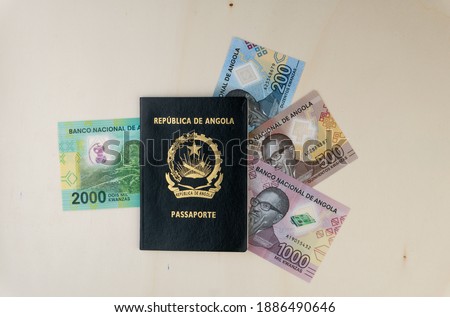 Angolan passport and new serie  of angolan banknotes of kwanza on wooden table. Top view. The rising costs of airline travel concept. 