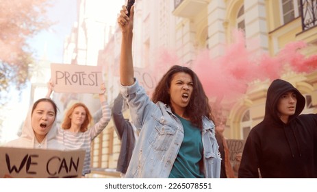 Angry activists protesters protesting in the city with posters, smoke bombs and fire flares.