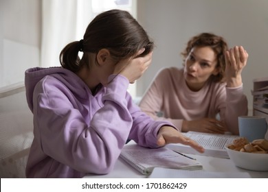 Angry adult mother scolding lazy teen daughter for bad school results at home. Frustrated mum talking to upset teenage girl arguing disciplining child must study. Parent and children conflicts concept