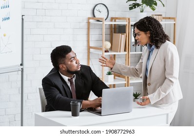 Angry African American Lady Boss Scolding Male Employee For Error In Urgent Project At Office. Displeased Businesswoman Reprimanding Black Worker For Missed Deadline. Workplace Stress Concept