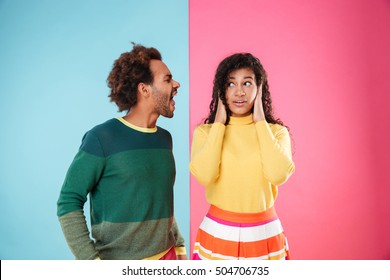 Angry african american young couple shouting on his girlfriend with covered ears