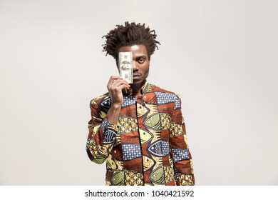 Angry African Man Holding One Dollar. Indoor, Isolated On Gray Background