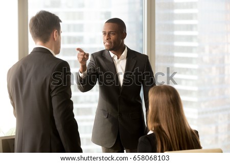 Angry african-american businessman threatens colleague, conflict between male workers at workplace, bullying and discrimination, black boss blames white employee responsible for failure, your fault