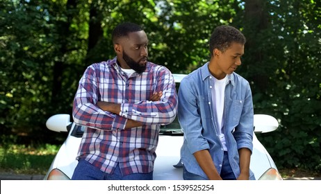 Angry Afro-american Father Looking At Guilty Teen Son Near Car, Family Conflict