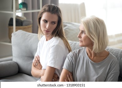 Angry aged mother and daughter looking at each other after quarrel, bad family relationships concept, parent and child conflict, different age generations, stubborn displeased women with arms crossed