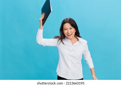 Angry Aggressive Cute Asian Businesswoman In Classic Office Dress Code Throwing Folder Tablet At Camera Posing Isolated On Over Blue Studio Background. Cool Business Offer. Job Interview Concept