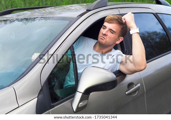 Angry aggressive guy, young emotional irritated\
man driver displeased, dissatisfied, frustrated while driving car\
threatening with fist from automobile window. Driving anger\
negative emotion\
agression