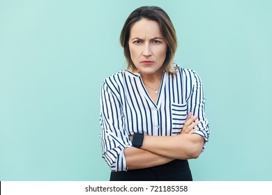 Angry, Aggressive. Handsome Elegant Woman Looking At Camera With Angry Face . Studio Shot, On Light Blue Background.