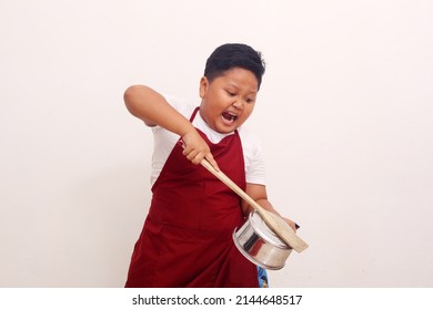 Angry Asian Boy With Apron Standing While Holding A Kitchen Ware. Cooking Class Concept