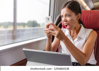 Angry Asian business woman upset screaming at phone call for communication problem or wifi internet connection during commute transport by train or bus. Worker working on laptop yelling mad.