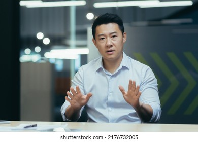 Angry Asian Businessman Talking On Video Call Online Meeting, Looking At Web Camera, Gesticulating Angrily With Hands, Man At Work In Office