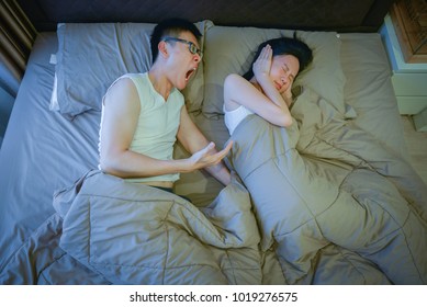 Angry Asian Couple Fighting On Bed At Night