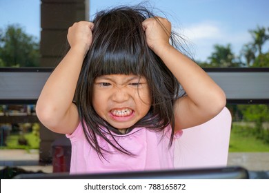 Angry Asian cute girl screaming after her mother take a tablet away. Stressed child,
Kid  with attention deficit hyperactivity disorder (ADHD) can't handle her emotion.

